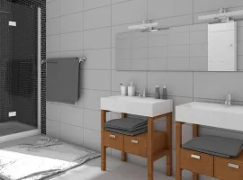 Renoviertes Badezimmer mit verschiedenen Wand- und Bodenfliesen, zwei Waschbecken und einer schwarzen Dusche