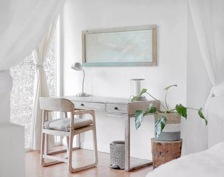 Seitenansicht eines weißen Zimmer mit Schreibtisch, Stuhl, Pflanze, und Bild an der Wand
