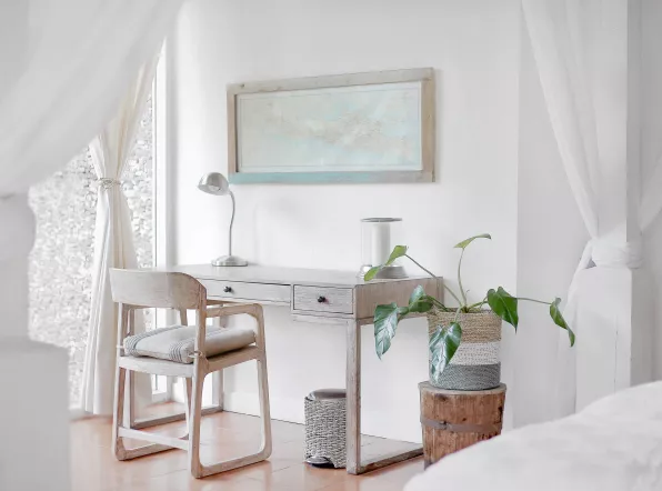 Weißes Zimmer mit Schreibtisch, Stuhl, Pflanze, und Bild an der Wand